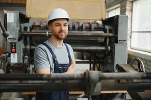 lächelnd und glücklich Mitarbeiter. industriell Arbeiter drinnen im Fabrik. jung Techniker mit Weiß schwer Hut. foto