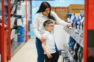 Frau mit Sohn wählen elektrisch Eisen im Elektronik Geschäft foto