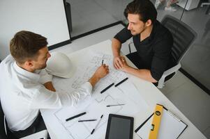 zwei Menschen sitzen im Vorderseite von Konstruktion planen und sich unterhalten Über das die Architektur foto