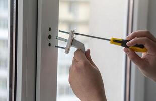 entfernen oder Installation das Griff auf das Fenster. Schutz gegen versehentlich Öffnung durch klein Kinder. Instandhaltung von Fenster Rahmen. klein Hausarbeit. Mann zum ein Stunde. foto