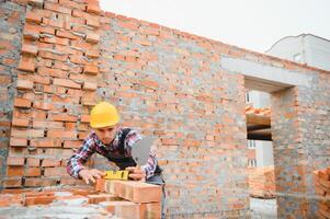 Ziegelmauer einbauen. bauarbeiter in uniform und sicherheitsausrüstung haben arbeit am bau foto