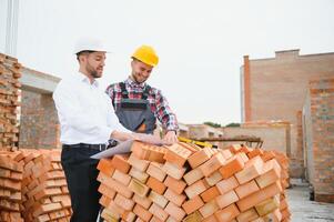 strukturell Ingenieur und Vorarbeiter Arbeiter diskutieren, planen Arbeiten zum das draußen Gebäude Konstruktion Seite? ˅ foto