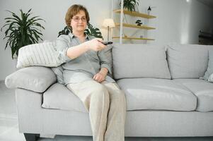 Menschen, Fernsehen und Unterhaltung Konzept - - Senior Frau im Brille mit Fernbedienung Steuerung Aufpassen Fernseher beim Zuhause foto