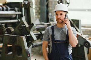 Verwaltung Team, Ingenieur, oder Vorarbeiter. Stehen Überprüfung Job Information Über industriell Produktion Verwaltung innerhalb das Fabrik durch Telefon. Zusammenarbeit Konzept foto