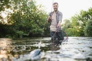Fischer fängt ein Forelle auf das Fluss im Sommer- foto