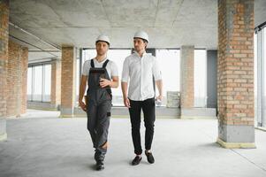 männlich Architekt geben Anleitung zu seine Vorarbeiter beim Konstruktion Seite? ˅. foto