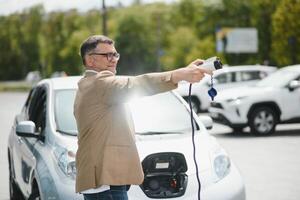 Mann halten Leistung Verbinder zum elektrisch Auto foto