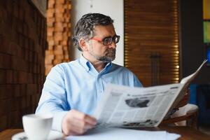 Zeitung im das Morgen. Senior Geschäftsmann beim seine Büro Reiten Zeitungen. foto