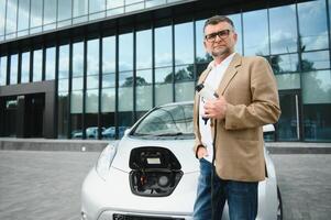 ein Geschäftsmann Gebühren ein elektrisch Auto foto