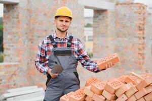 Konstruktion Arbeiter Mann im Arbeit Kleider und ein Konstruktion Helm. Porträt von positiv männlich Baumeister im Helm Arbeiten beim Konstruktion Seite? ˅. foto