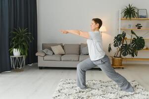 Erwachsene Frau tun Fitness Übungen beim heim. Senior Frau tun Dehnen Übungen. reifen Frau tun Yoga posiert foto
