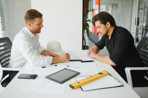 zwei Menschen sitzen im Vorderseite von Konstruktion planen und sich unterhalten Über das die Architektur foto