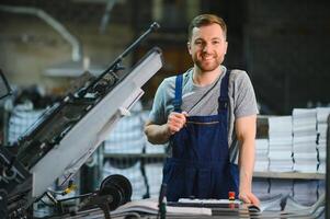 Porträt von Produktion Linie Arbeiter steuern Herstellung Prozess von modern Verpackung industriell Maschine im Drucken Fabrik foto