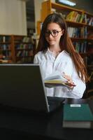 im das Bibliothek - - ziemlich weiblich Schüler mit Bücher Arbeiten im ein hoch Schule Bibliothek. foto