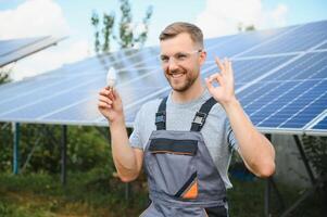 ein Mann hält ein weißglühend Licht Birne im seine Energie Konzept, das Sonne ist sauber nach Arbeit und ersetzt das Energie Das produziert Kohlenstoff Dioxid. foto