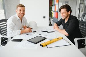 zwei Menschen sitzen im Vorderseite von Konstruktion planen und sich unterhalten Über das die Architektur foto