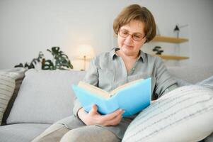 Porträt von attraktiv konzentriert heiter Frau Sitzung auf Diwan lesen Buch Zeitvertreib Tagtraum beim Zuhause Haus eben drinnen. foto