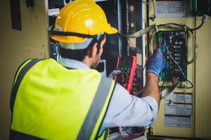 elektrisch Ingenieur Arbeit Prüfer Messung Stromspannung und Strom von Leistung elektrisch Linie im elektrisch Kabinett Steuerung zum industriell Produktion. foto