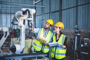 Mechaniker des Ingenieurteams, der den Roboterarm der Computersteuerung zum Schweißen von Stahl in der Werkstatt der Stahlfabrik verwendet. Programmiersoftware für Industrieroboter für die automatisierte Fertigungstechnik foto