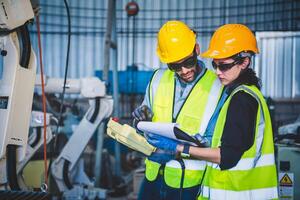 Mechaniker des Ingenieurteams, der den Roboterarm der Computersteuerung zum Schweißen von Stahl in der Werkstatt der Stahlfabrik verwendet. Programmiersoftware für Industrieroboter für die automatisierte Fertigungstechnik foto