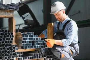 Porträt von Fabrik Arbeiter im schützend Uniform und Helm Stehen durch industriell Maschine beim Produktion Linie. Menschen Arbeiten im Industrie foto