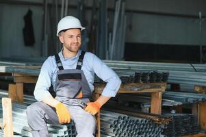 Porträt von Fabrik Arbeiter im schützend Uniform und Helm Stehen durch industriell Maschine beim Produktion Linie. Menschen Arbeiten im Industrie foto