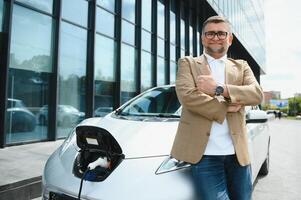 ein Geschäftsmann Gebühren ein elektrisch Auto foto