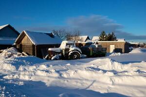 rustikal Winter Landschaft mit ein Traktor im das Schnee und Häuser. foto