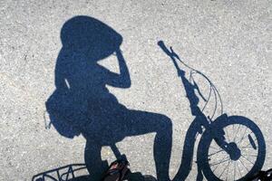 Schatten von Radfahrer anhalten zum sich ausruhen auf ein Fahrrad auf ein Straße foto
