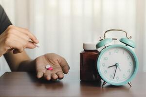 Person halten ein Pille mit ein Medizin Flasche und ein Alarm Uhr foto