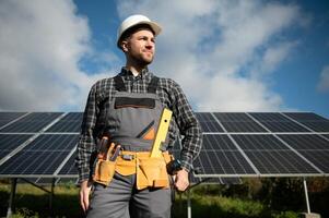 Experte ist inspizieren Qualität von ein Solar- Batterien. Arbeiter im Uniform und Helm mit Ausrüstung. Ökologie Leistung Erhaltung Konzept. foto