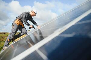 Experte ist inspizieren Qualität von ein Solar- Batterien. Arbeiter im Uniform und Helm mit Ausrüstung. Ökologie Leistung Erhaltung Konzept. foto