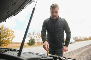 Mann mit gebrochen Auto im das Mitte von das Straße. foto