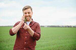 jung gut aussehend Farmer Gehen auf Ackerland, und reden auf Zelle Telefon foto
