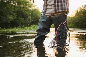 Fischer fängt ein Forelle auf das Fluss im Sommer- foto