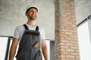 Porträt von gut aussehend männlich Baumeister im Overall und schwer Hut foto