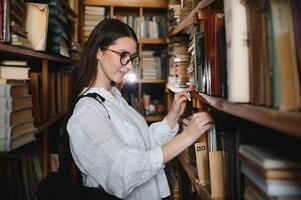 im das Bibliothek - - ziemlich weiblich Schüler mit Bücher Arbeiten im ein hoch Schule Bibliothek. foto