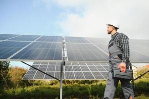 Experte ist inspizieren Qualität von ein Solar- Batterien. Arbeiter im Uniform und Helm mit Ausrüstung. Ökologie Leistung Erhaltung Konzept. foto