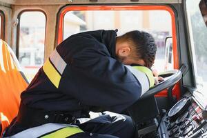 Feuerwehrmann beim das Rad von ein Notfall Fahrzeug fährt zu das Szene von Aktion und erlischt Feuer. foto