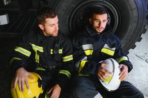 Porträt von zwei heroisch Feuerwehrmann im schützend passen und Helm. foto