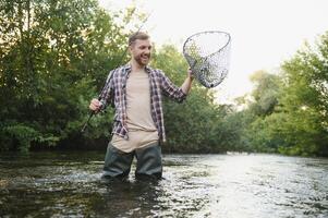 Fischer fängt ein Forelle auf das Fluss im Sommer- foto