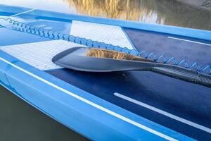 Detail von Stand oben Paddel Boot mit ein Paddel und Sicherheit Leine foto