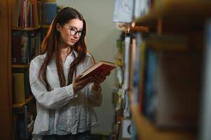 im das Bibliothek - - ziemlich weiblich Schüler mit Bücher Arbeiten im ein hoch Schule Bibliothek. foto