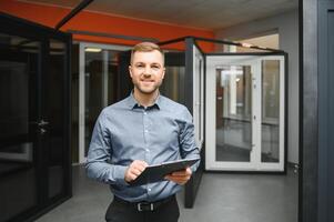 freundlich Verkäufer im Fenster Geschäft mit Schlüssel. ein groß Auswahl von Fenster und Türen zum das Haus. Zuhause Renovierung konzept foto