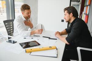 zwei Menschen sitzen im Vorderseite von Konstruktion planen und sich unterhalten Über das die Architektur foto