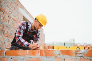 Konstruktion Arbeiter Mann im Arbeit Kleider und ein Konstruktion Helm. Porträt von positiv männlich Baumeister im Helm Arbeiten beim Konstruktion Seite? ˅. foto