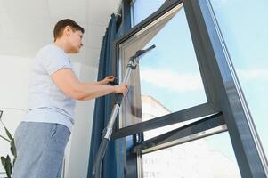 ein attraktiv mittleren Alters Frau ist Waschen ein Fenster im ein Zimmer foto