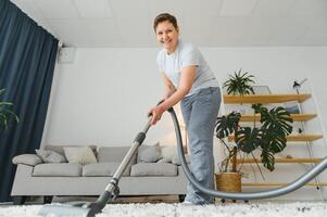 Reinigung Konzept. Frau Reinigung Teppich mit Vakuum Reiniger. foto