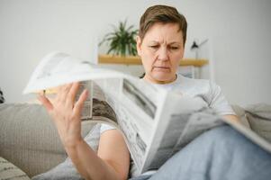 Frau Sitzung lesen das Zeitung beim heim. foto