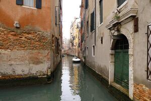 typisch eng Straßen und Kanäle zwischen bunt und schäbig Häuser im Venedig, Italien. historisch die Architektur im Venedig, geparkt Boote auf das Kanäle. foto